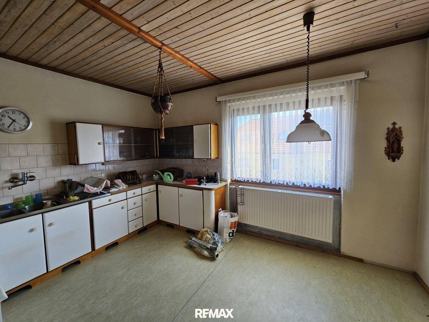 Geräumige Küche mit Einbauschränken, Holzdecke und großem Fenster.
