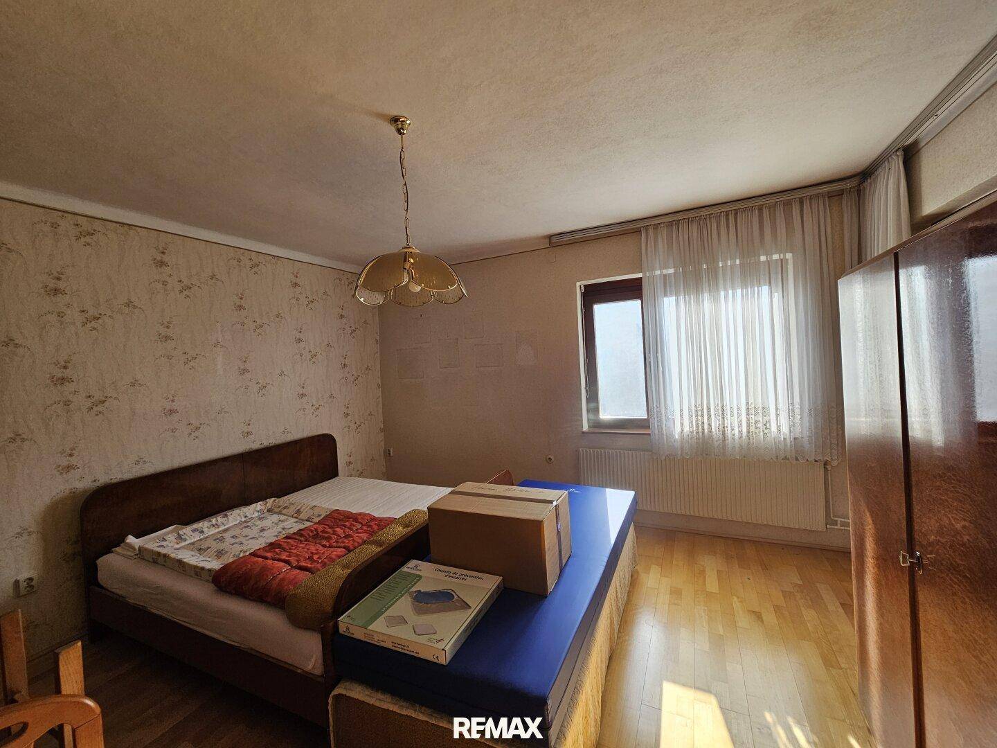 Schlafzimmer mit Holzboden, Bett und Fenster, bereit zur individuellen Gestaltung.
