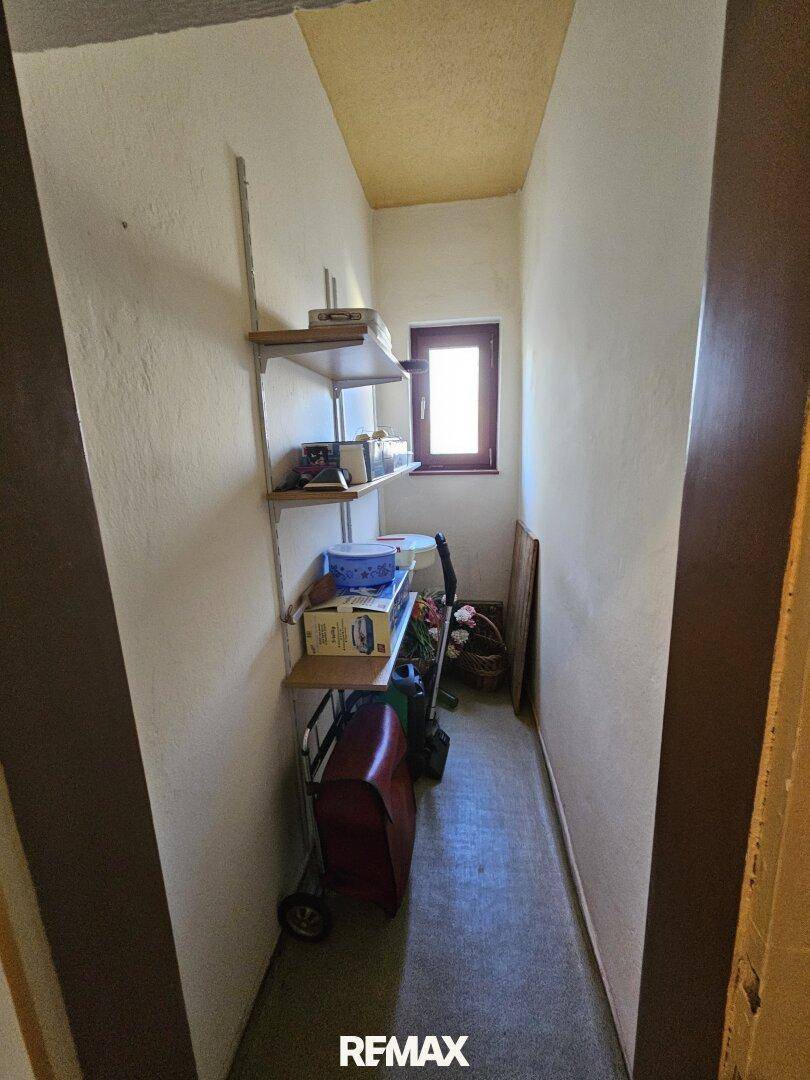 Schmaler Abstellraum mit Regalen, kleinem Fenster und Stauraum für Haushaltsgeräte.