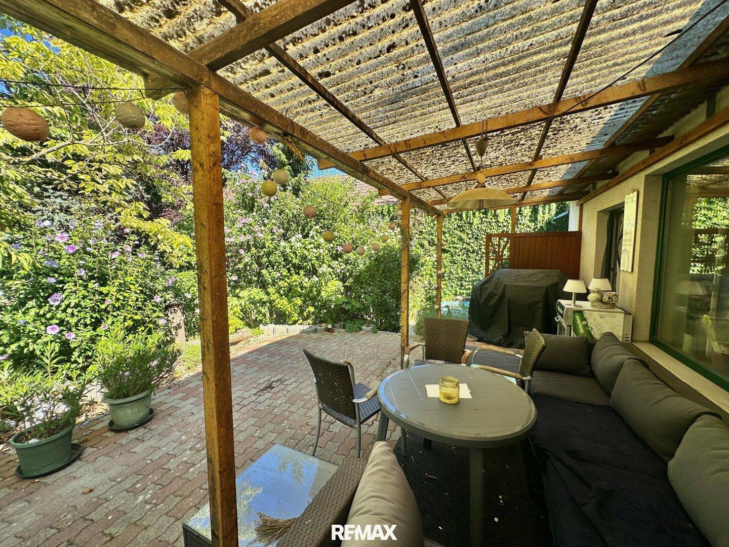 Gemütliche überdachte Terrasse mit Lounge-Möbeln und Blick ins Grüne.