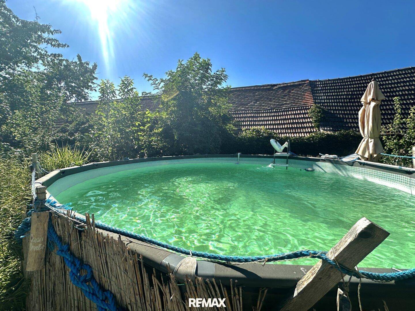 Aufstellpool im sonnigen Gartenbereich mit Blick auf das Hauptgebäude.