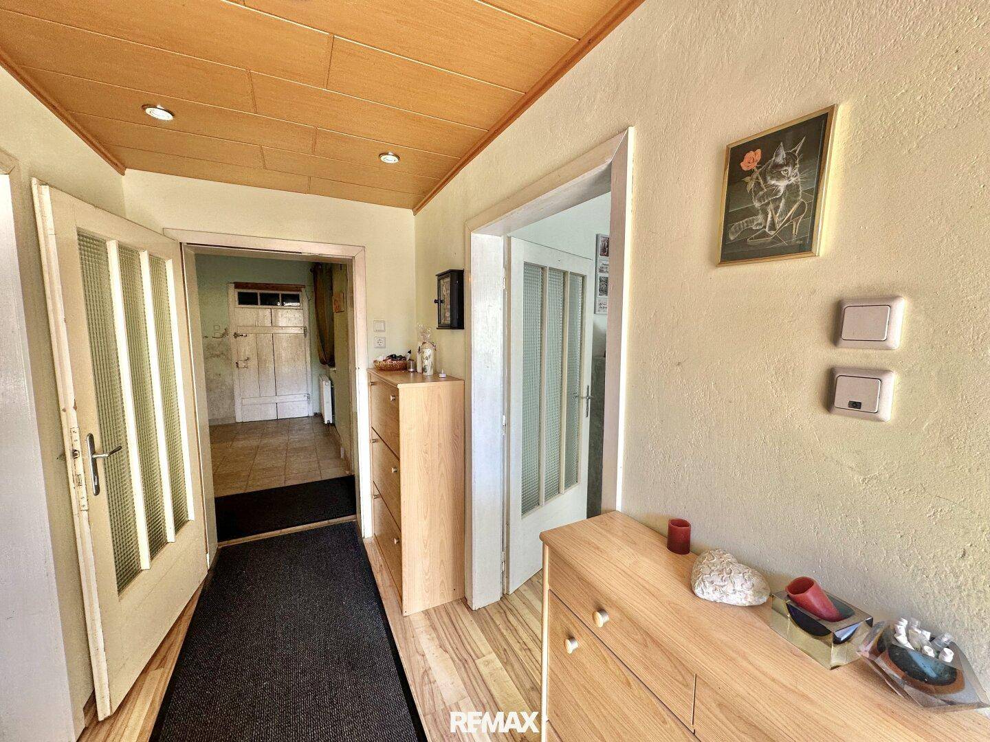 Heller Flur mit Holzdecke, Kommode und Zugang zu weiteren Räumen.