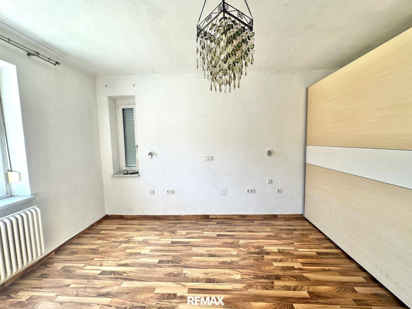 Leeres Schlafzimmer mit Holzboden, großem Kleiderschrank und Kronleuchter.