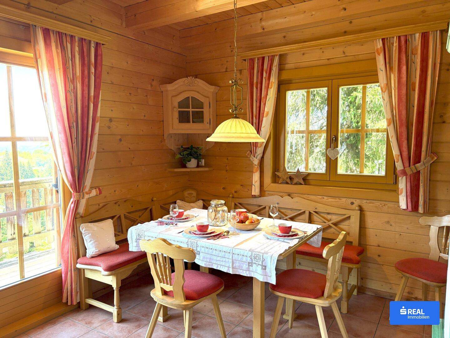 Rustikaler Essbereich mit Holzwänden und -decke, einem gedeckten Tisch und traditionellen Vorhängen.