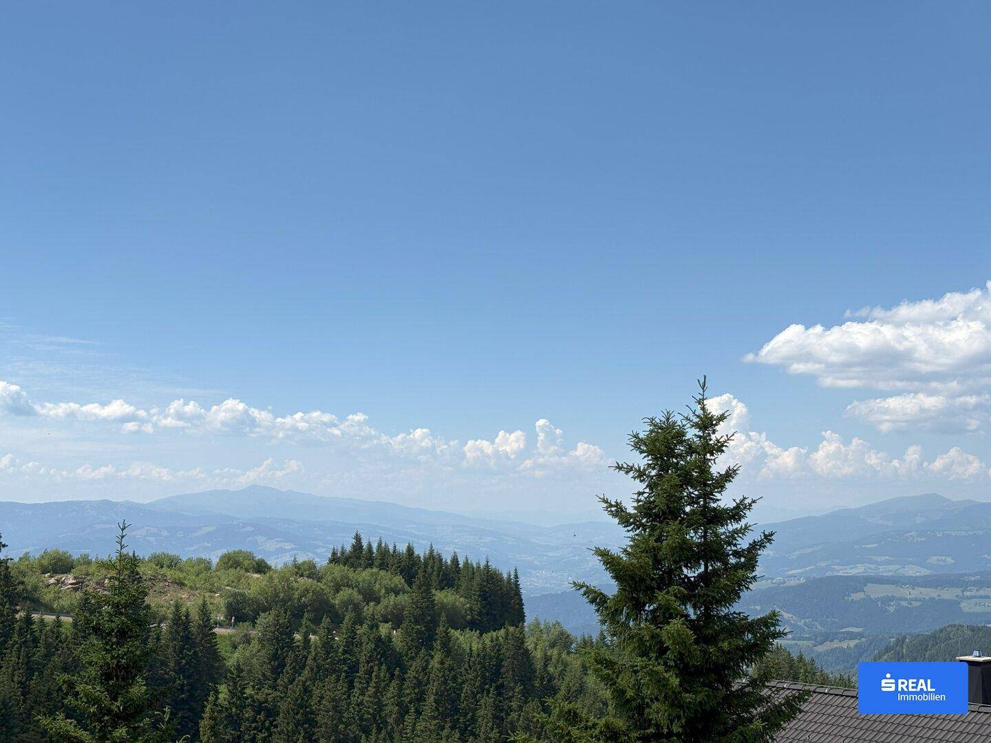 Weitläufiger Panoramablick auf eine beeindruckende Berglandschaft unter strahlend blauem Himmel.