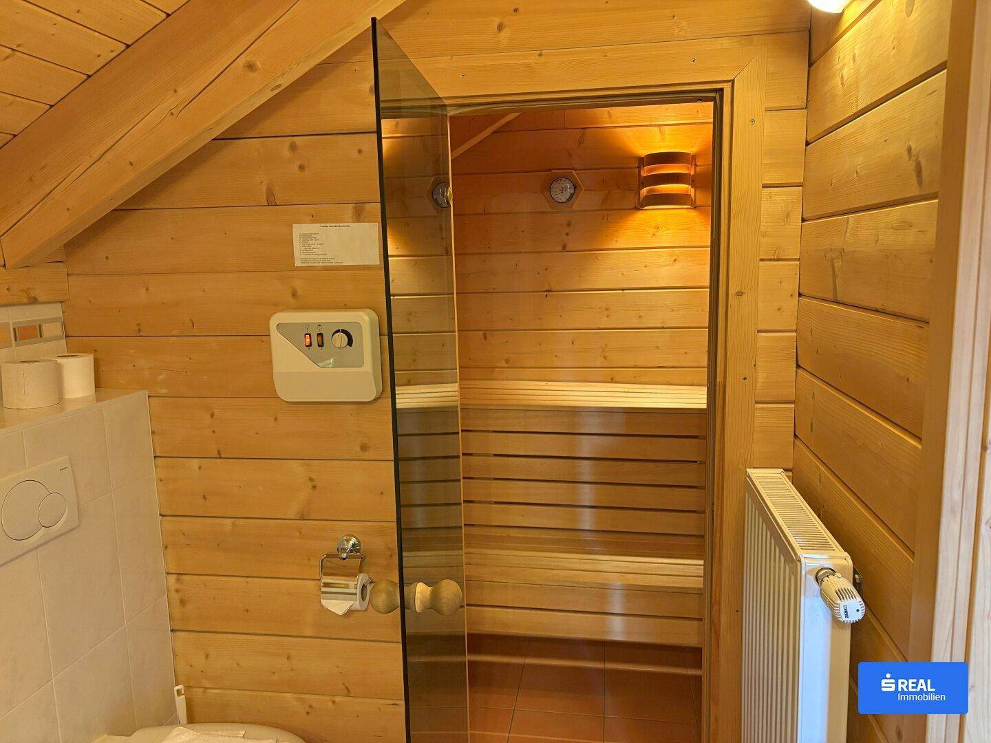 Innenansicht der Holzsauna mit Sitzbänken und Heizofen für entspannende Momente.