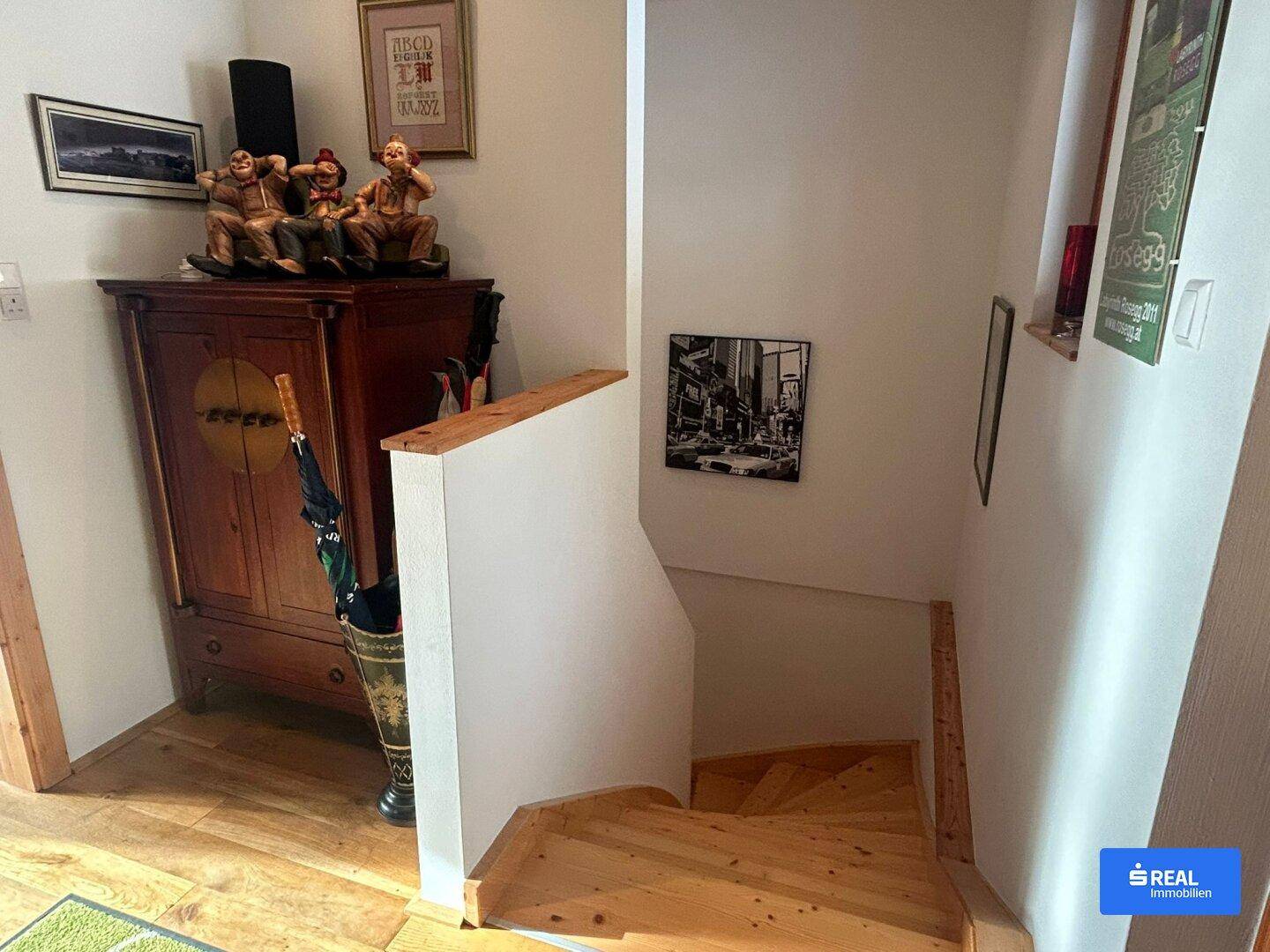 Treppenbereich mit Holzstufen und einem antiken Holzschrank im Flur.