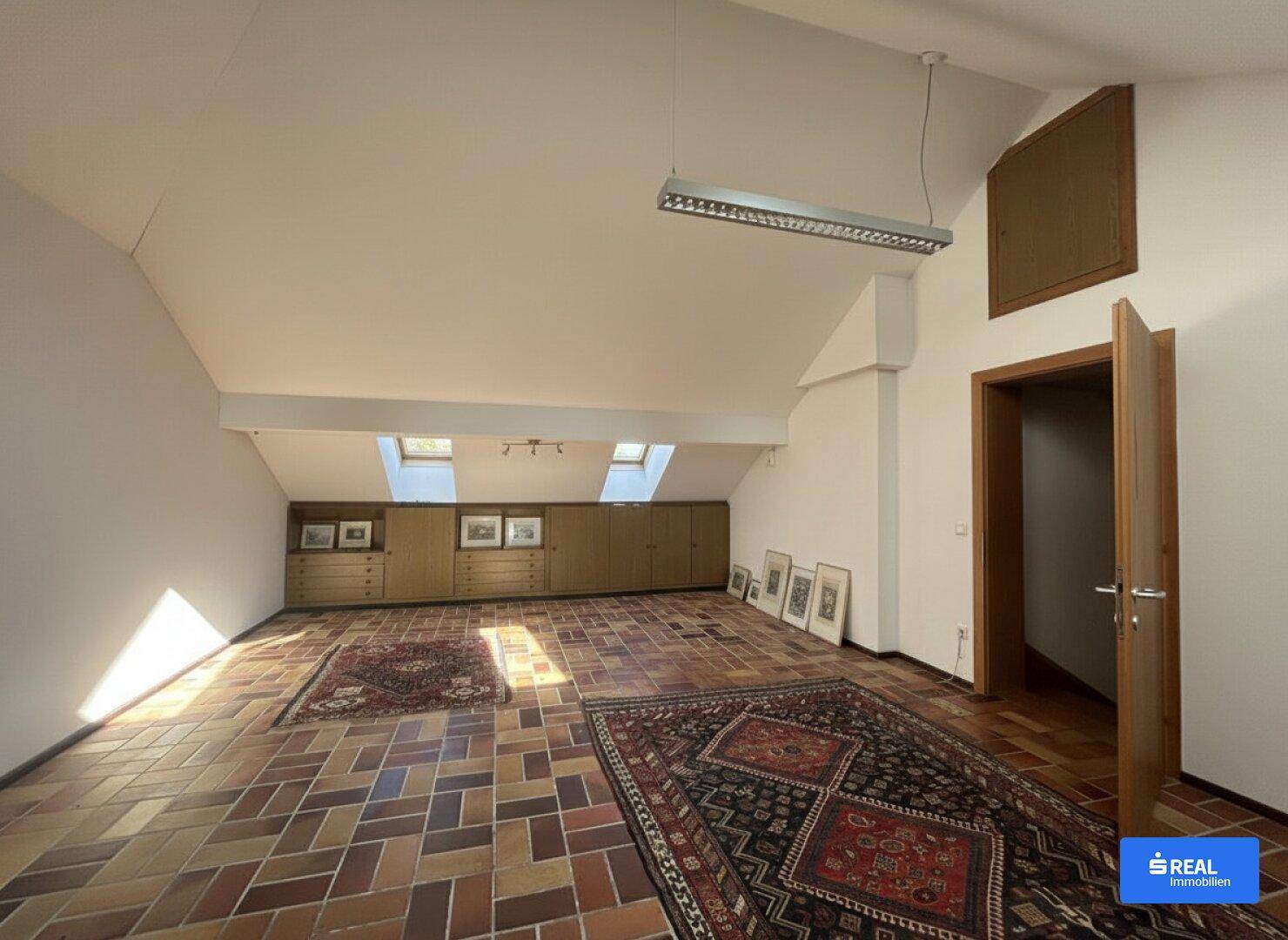 Geräumiger Dachbodenraum mit Dachschrägen, Dachfenstern und Terrakottafliesen.