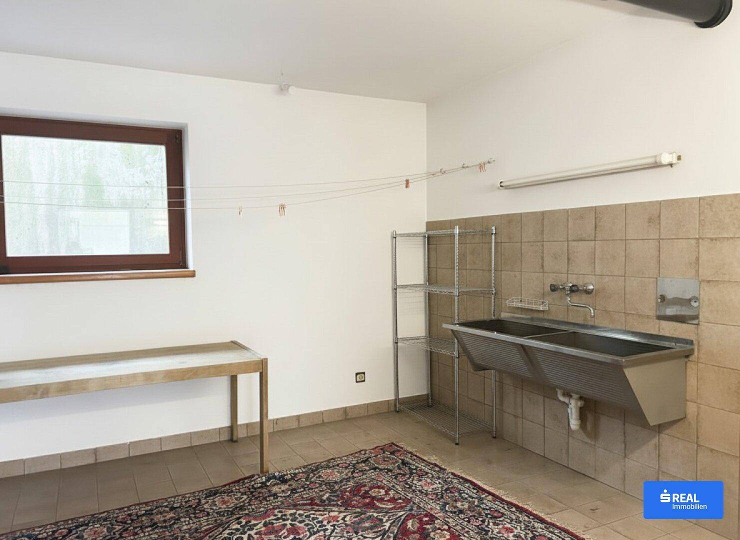 Praktischer Hauswirtschaftsraum mit Waschbecken, Regalen und Fenster für Belüftung.