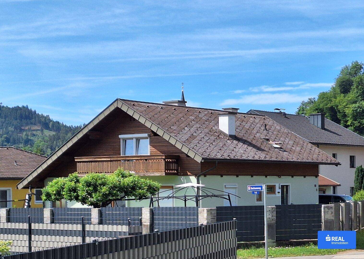 Einfamilienhaus mit Satteldach, Balkon und Blick auf die umliegende Berglandschaft.