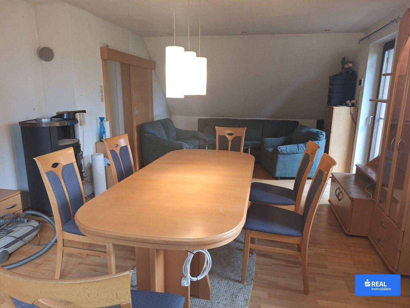 Gemütlicher Wohn-Essbereich mit Holztisch, Sofa und Dachschrägen, ideal für gesellige Abende.