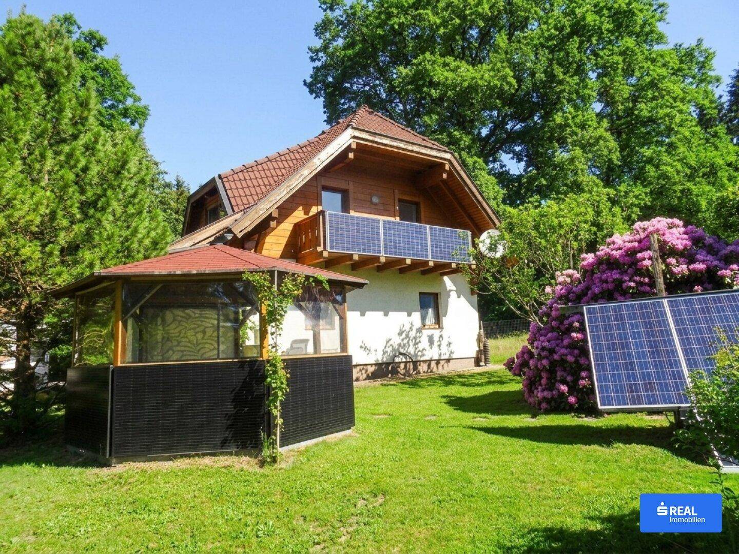 Charmantes Haus mit Photovoltaikanlage auf dem Dach und einem Pavillon im grünen Garten.