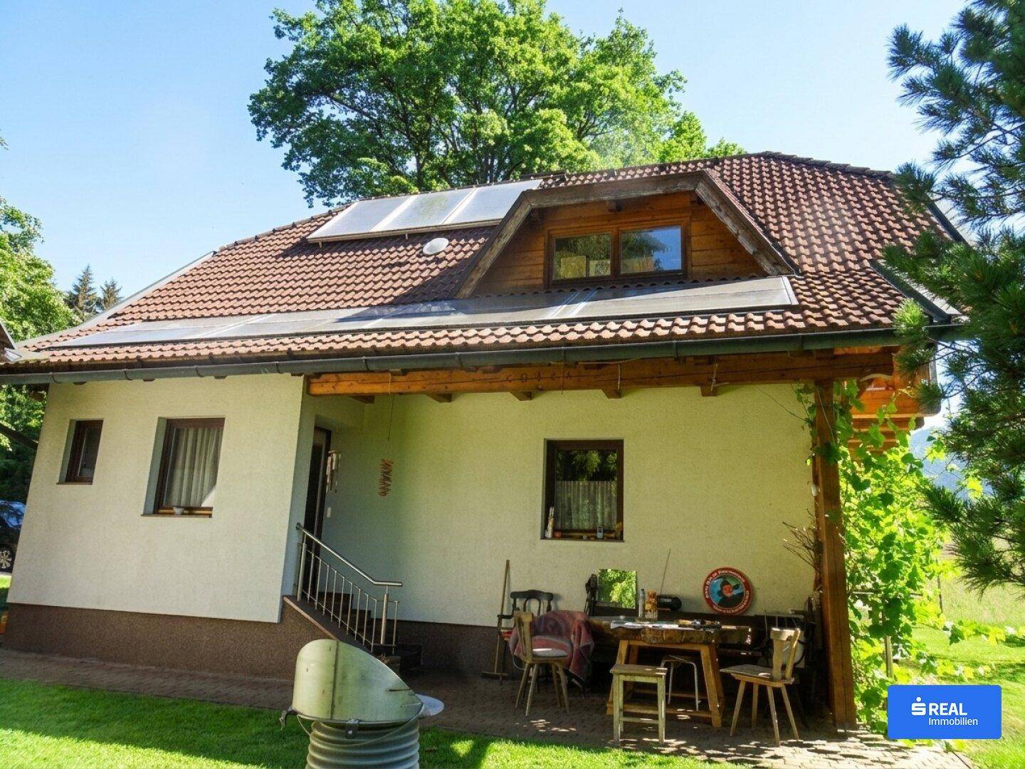 Rückansicht des Hauses mit Photovoltaikmodulen auf dem Dach und einem kleinen Außenbereich.