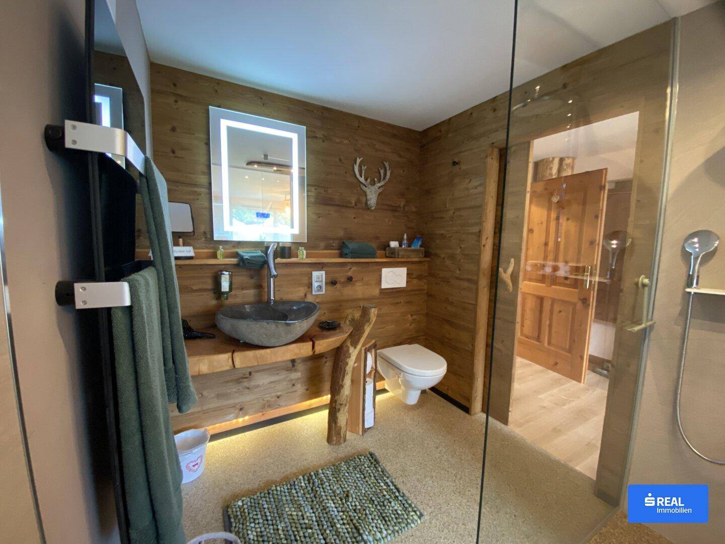 Modernes Badezimmer mit Holzverkleidung, Steinwaschbecken und ebenerdiger Dusche.