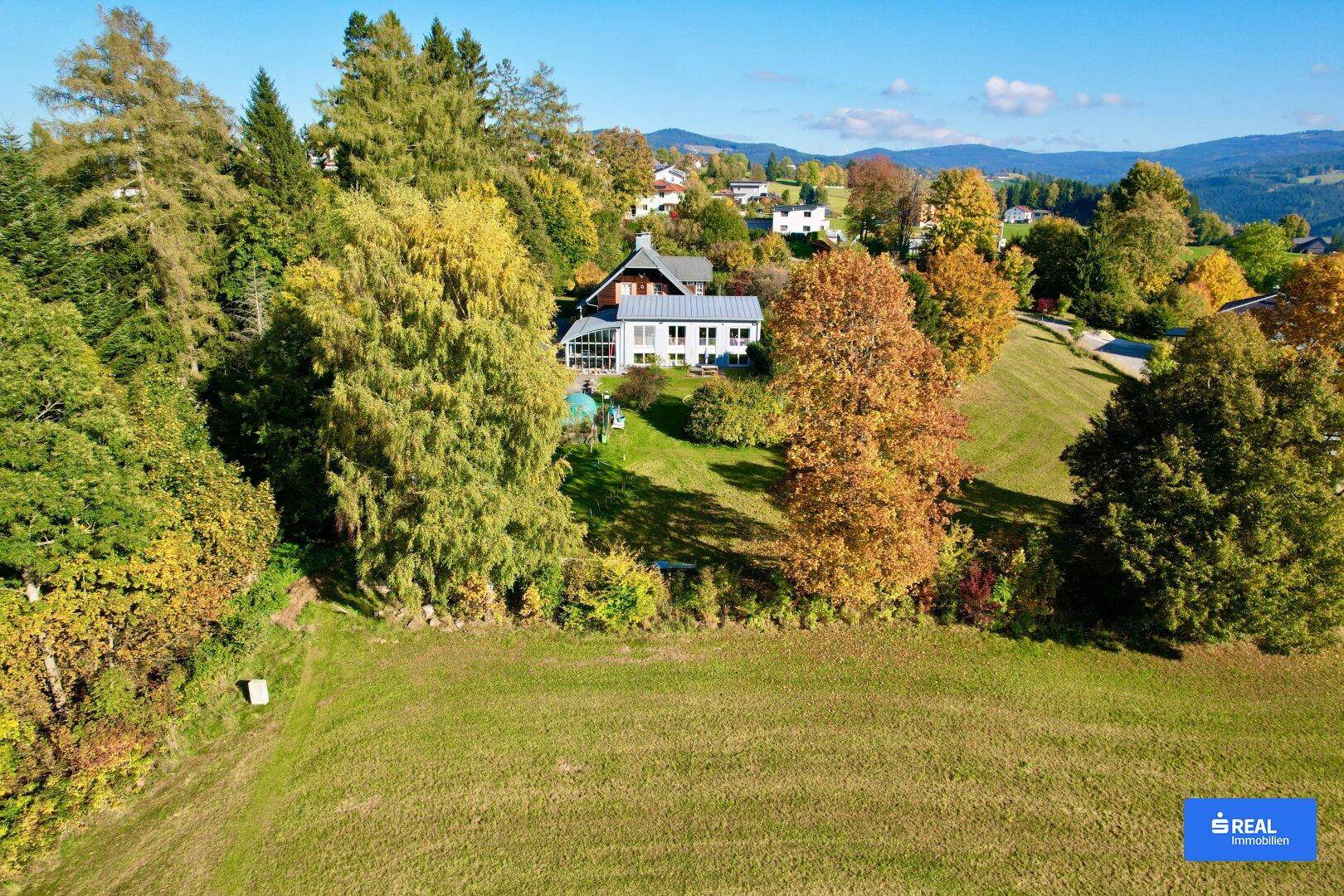 Weitläufiges Anwesen in ländlicher Umgebung mit viel Grün und Herbstbäumen.