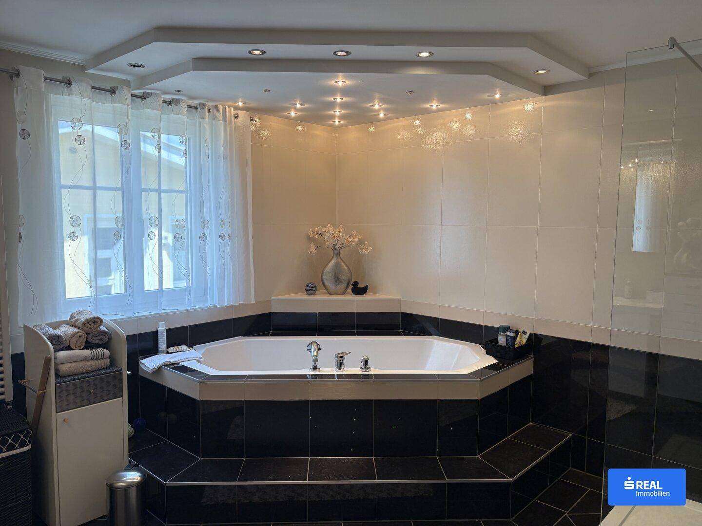 Modernes Badezimmer mit Eckbadewanne, Einbaustrahlern und großen Fliesen.