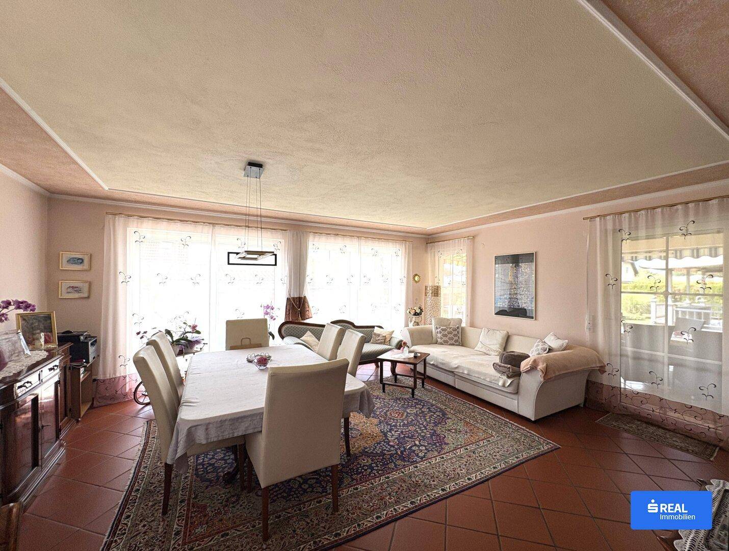 Geräumiger Wohn-Essbereich mit Terrakottaboden, großem Esstisch und bequemen Sofas.