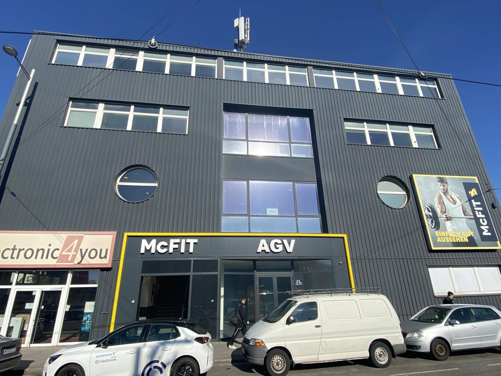Moderne Geschäftsfassade mit dunkler Verkleidung, großen Fenstern und mehreren Ladenlokalen im Erdgeschoss.