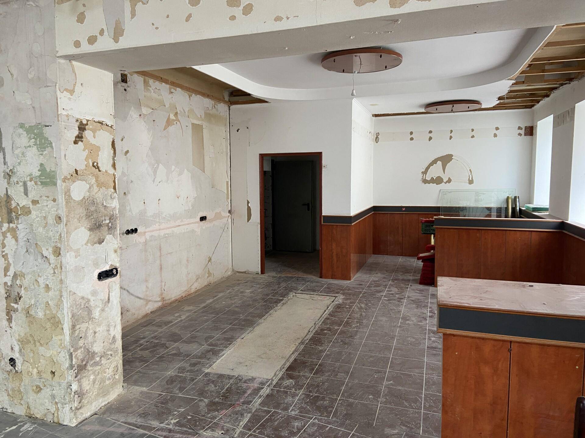 Weiterer Blick in den renovierungsbedürftigen Innenraum mit freigelegten Wänden und einem Durchgang.