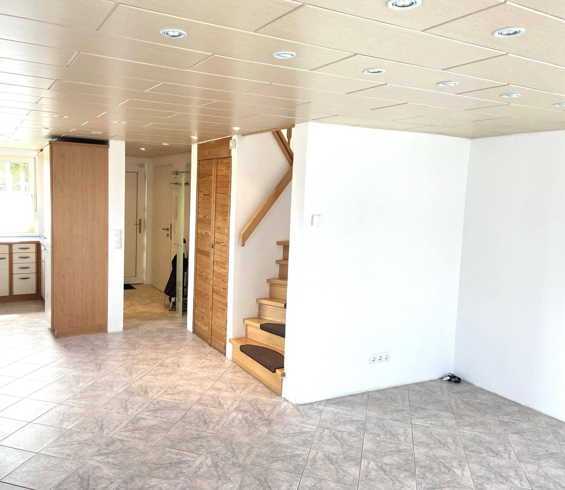 Geräumiger Wohnbereich mit Fliesenboden und Holztreppe, die zu den oberen Etagen führt.