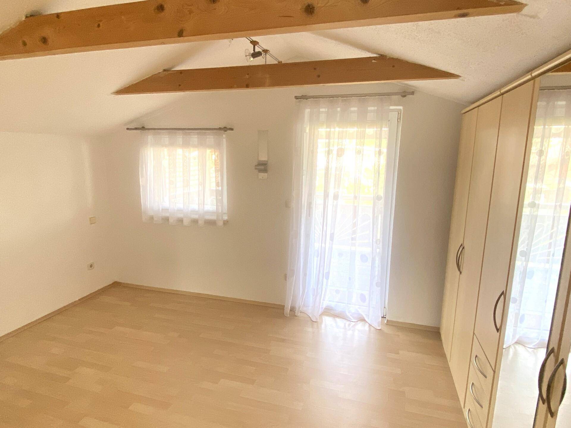 Schlafzimmer mit Laminatboden, Zugang zum Balkon und viel natürlichem Lichteinfall.