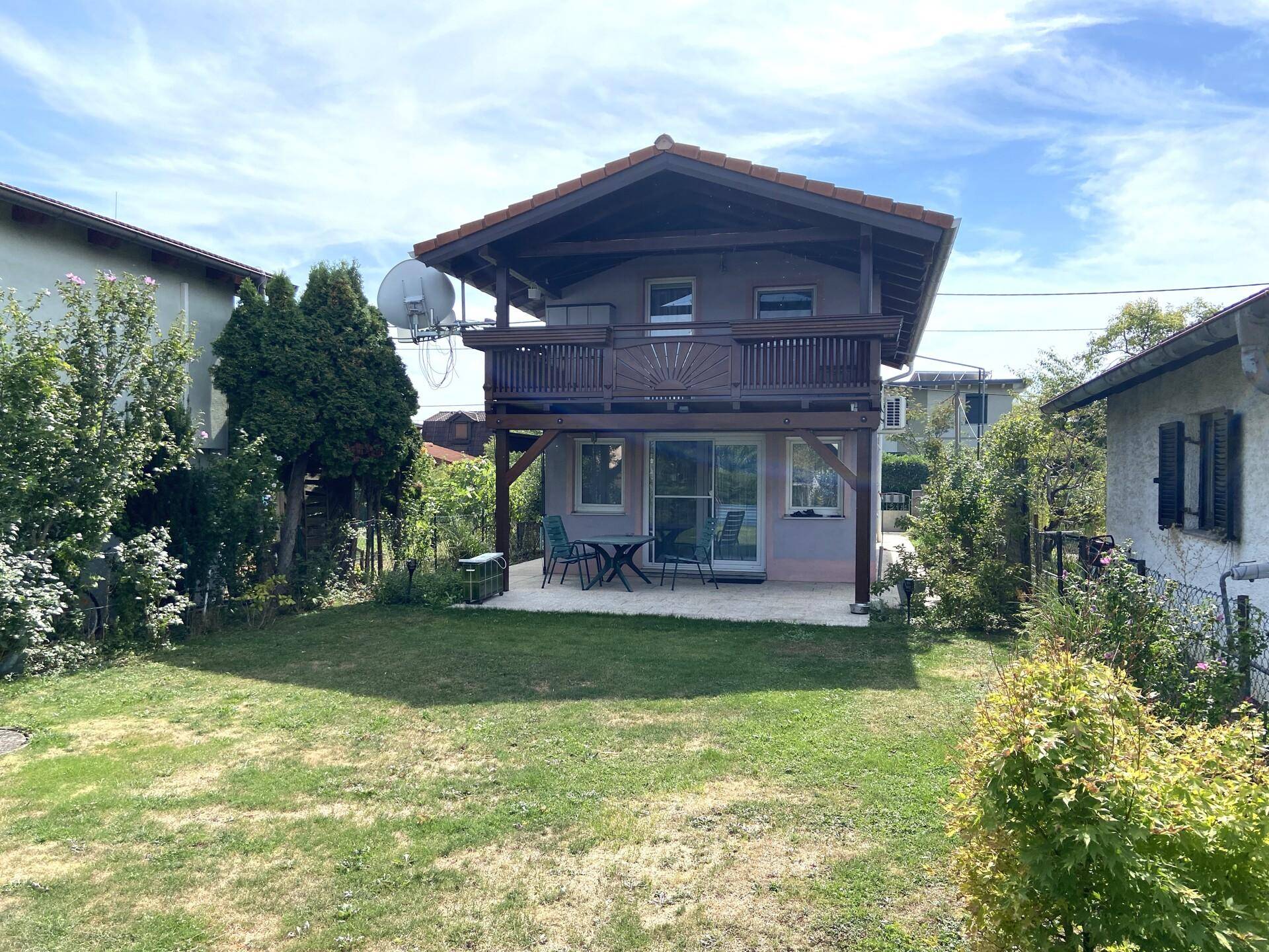 Rückseite des Hauses mit großem Garten, Rasenfläche und einem Balkon im Obergeschoss.
