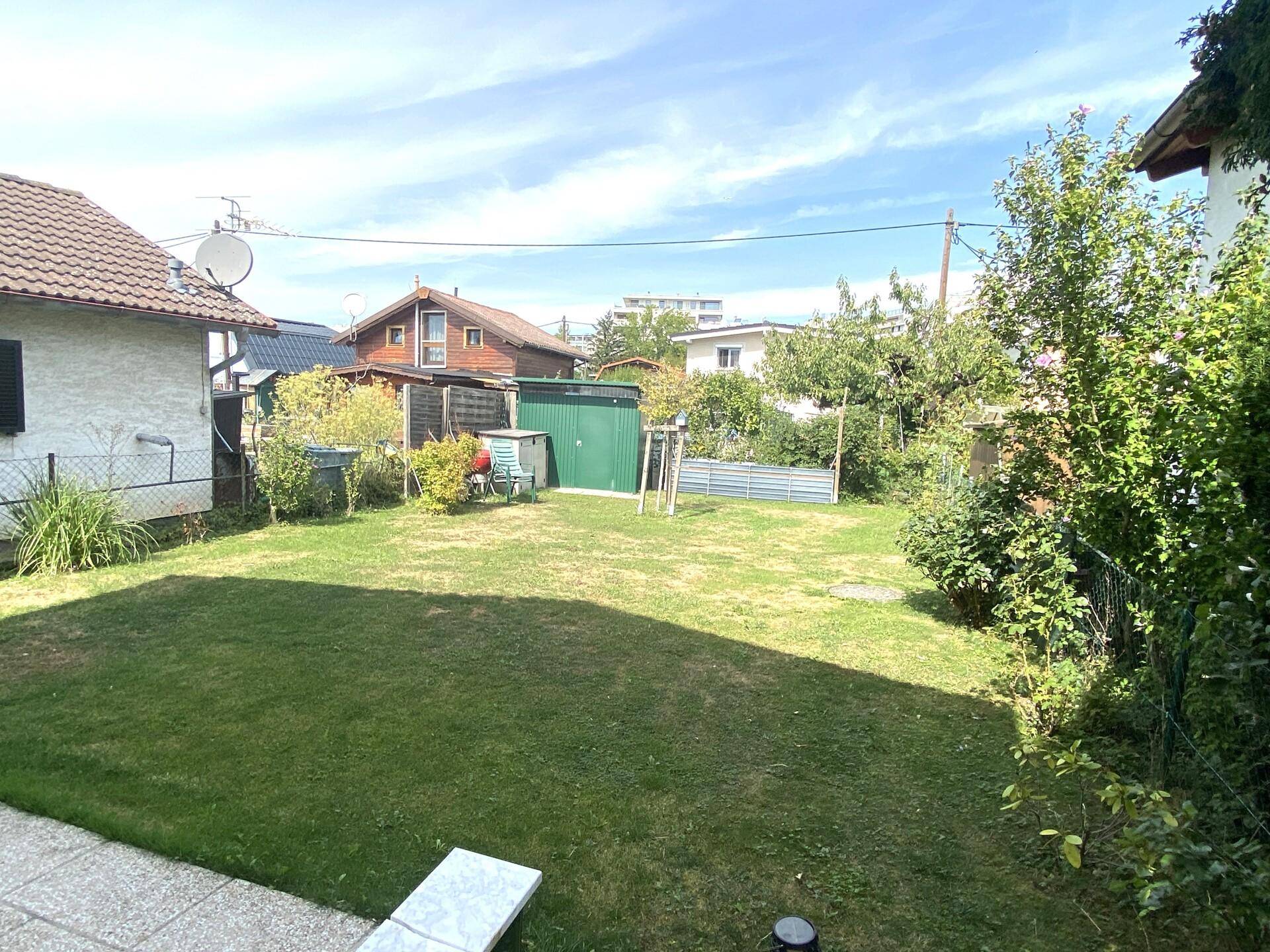 Weitläufiger Gartenbereich mit gepflegtem Rasen und Blick auf benachbarte Gebäude.