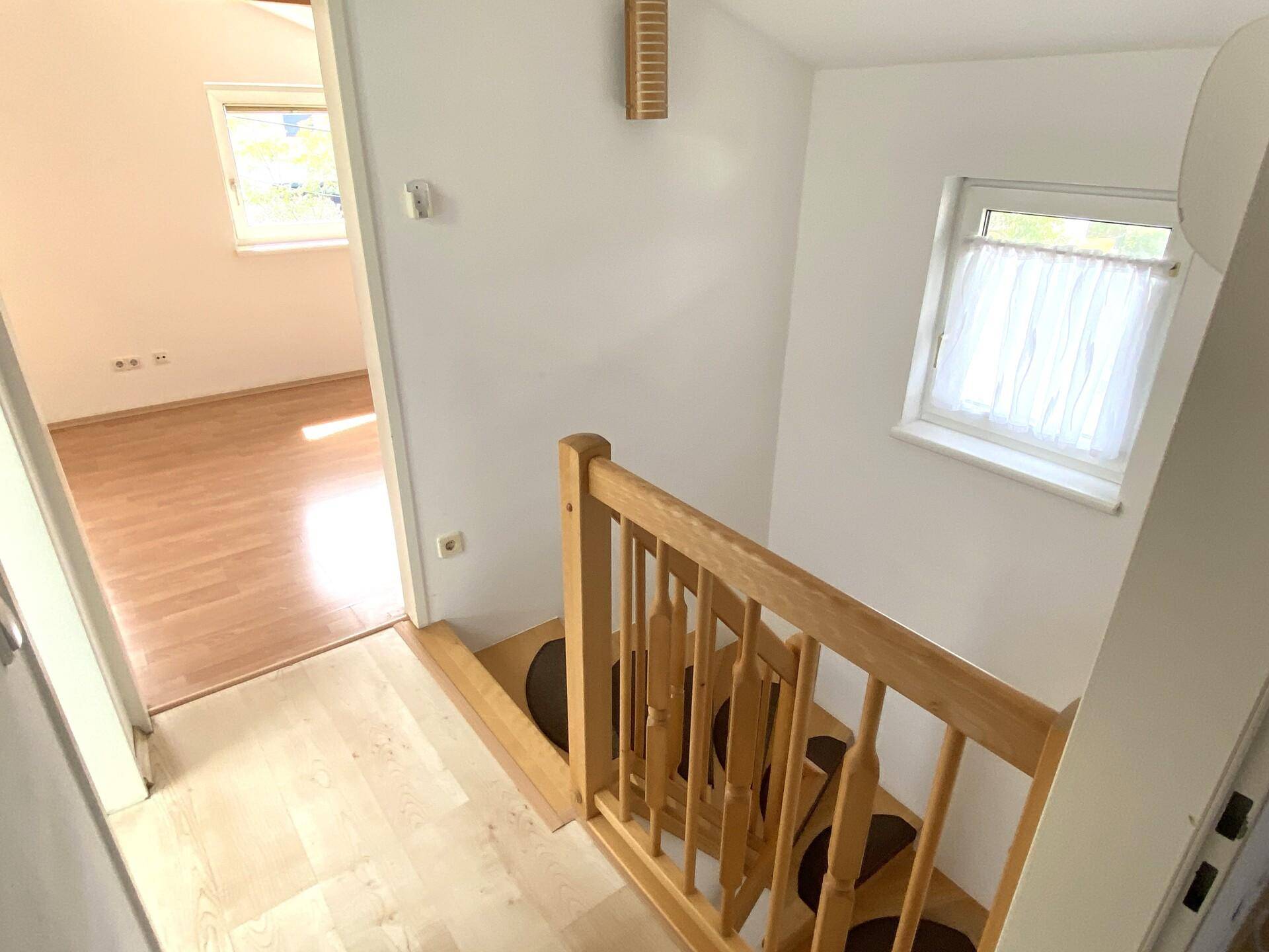 Heller Flur mit Holztreppe und Zugang zu den oberen Zimmern des Hauses.