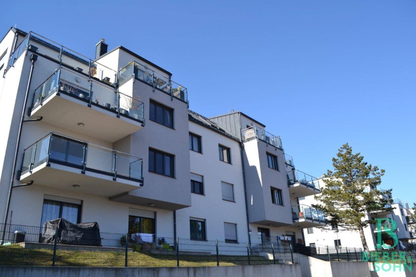 Moderne Wohnanlage mit mehreren Balkonen und zeitgenössischer Architektur unter blauem Himmel.
