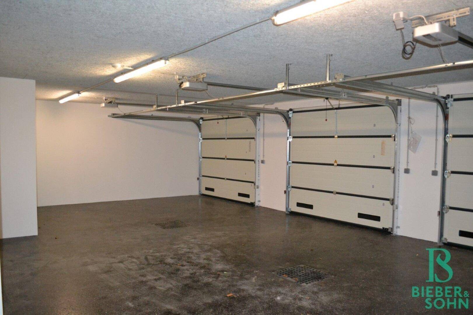 Geräumige Tiefgarage mit mehreren Garagentoren und einfacher Beleuchtung.