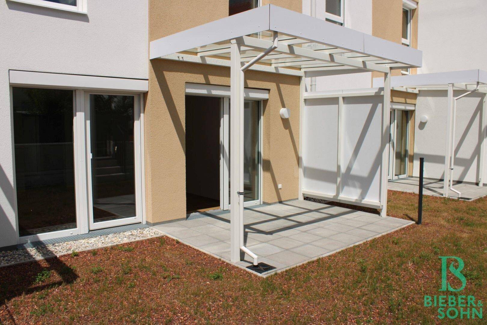 Sonniger Terrassenbereich mit Überdachung und Zugang zum Garten, ideal für Entspannung.