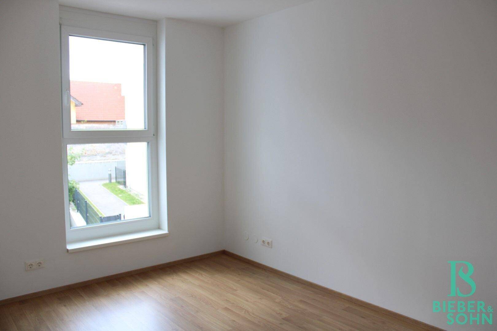 Helles Schlafzimmer mit Holzboden und großem Fenster, bietet viel Tageslicht.