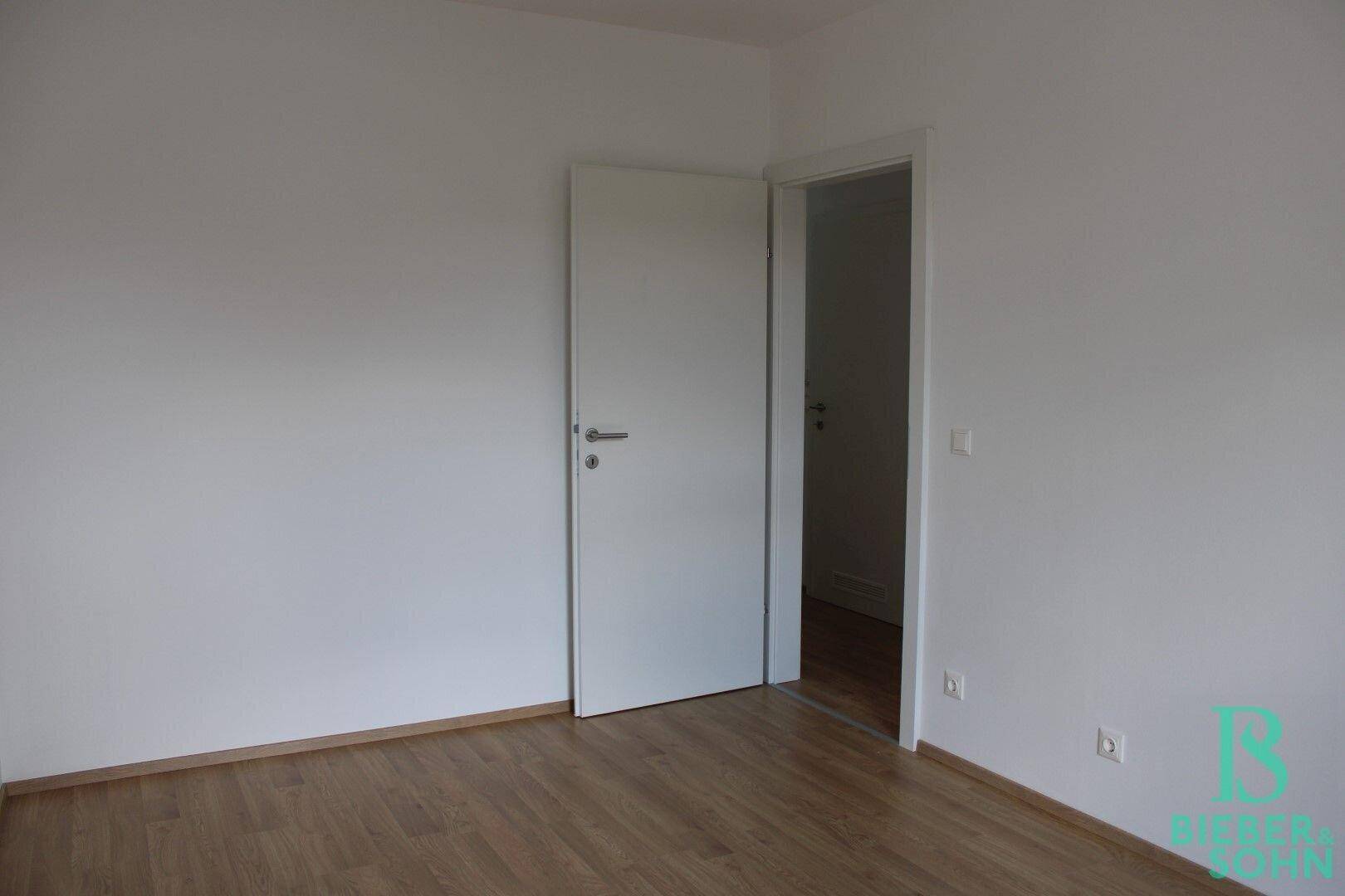 Geräumiges Schlafzimmer mit Holzboden und weiß gestrichenen Wänden, bereit zum Einzug.