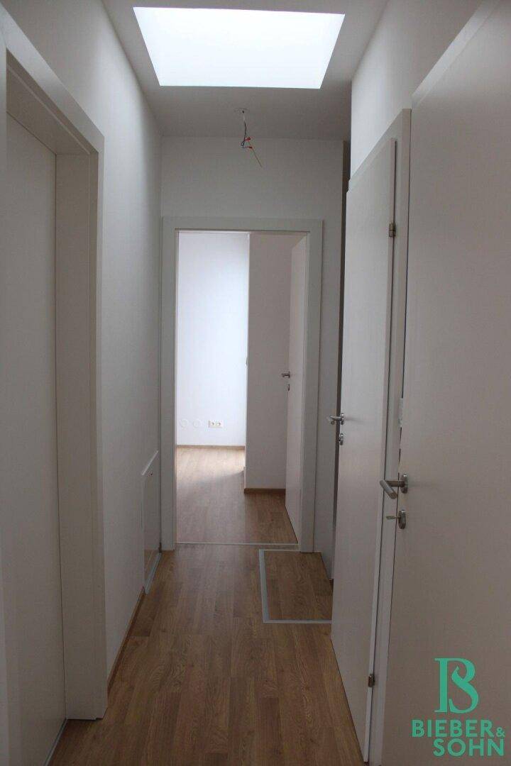 Heller Flur mit Laminatboden und Oberlicht, der zu weiteren Räumen führt.