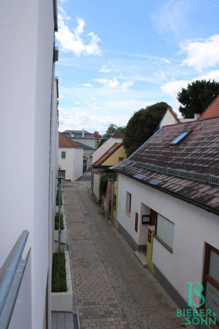Blick von einem Balkon auf eine ruhige Gasse und umliegende Dächer.