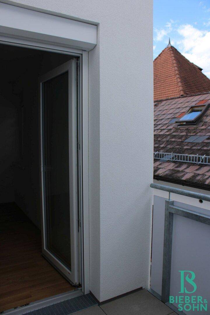 Detailansicht eines Balkons mit Tür und Blick auf ein traditionelles Dach.