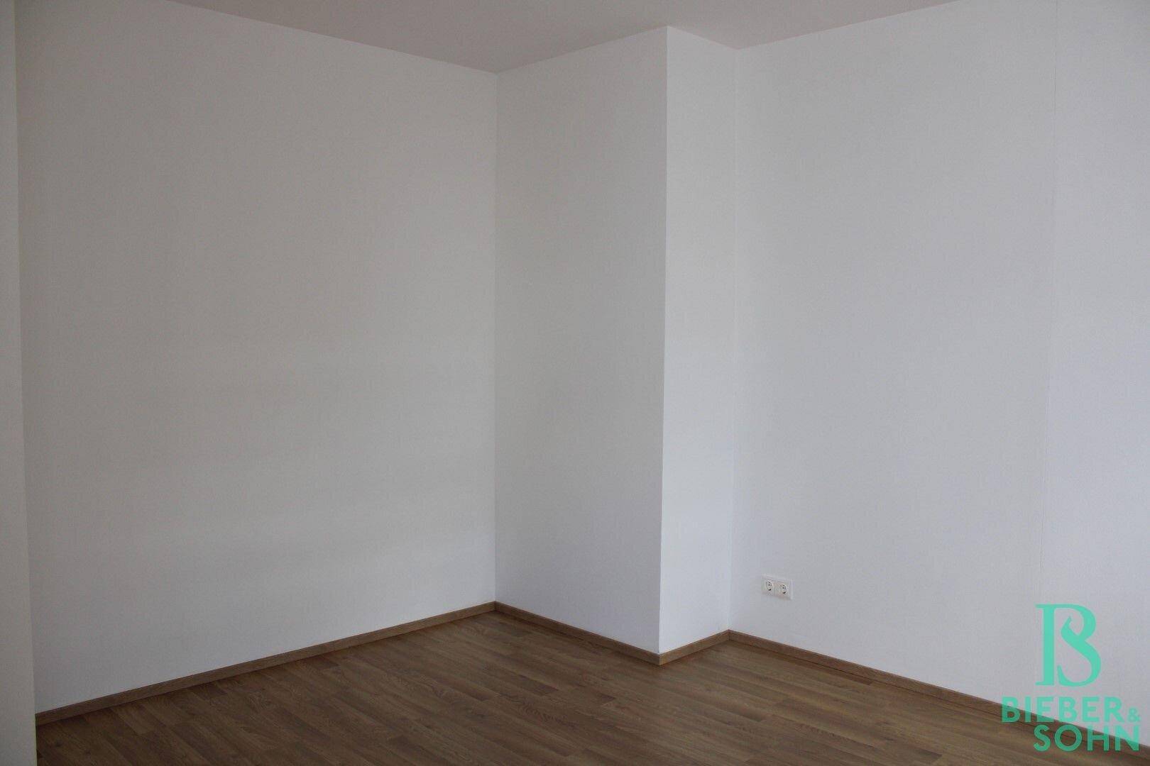 Leeres Zimmer mit Holzboden und weißen Wänden, bietet viel Gestaltungspotenzial.