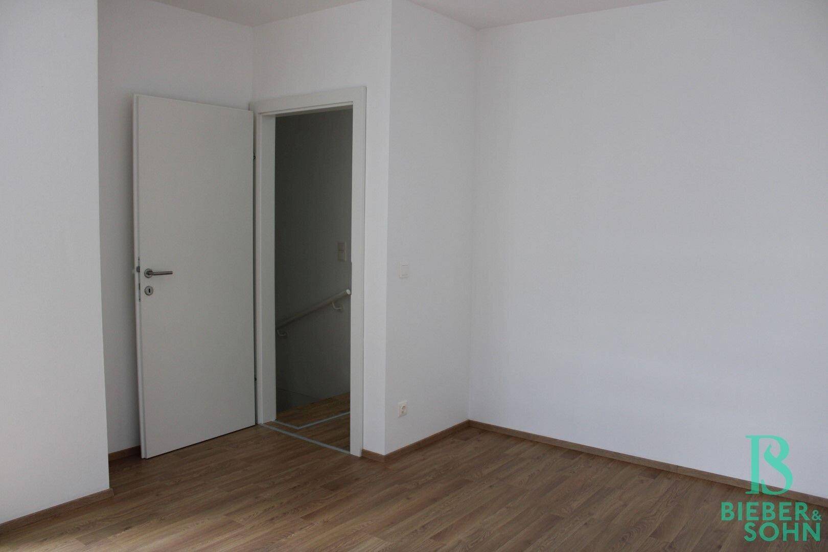Geräumiges Zimmer mit Holzboden und weiß gestrichenen Wänden, ideal als Schlafzimmer.