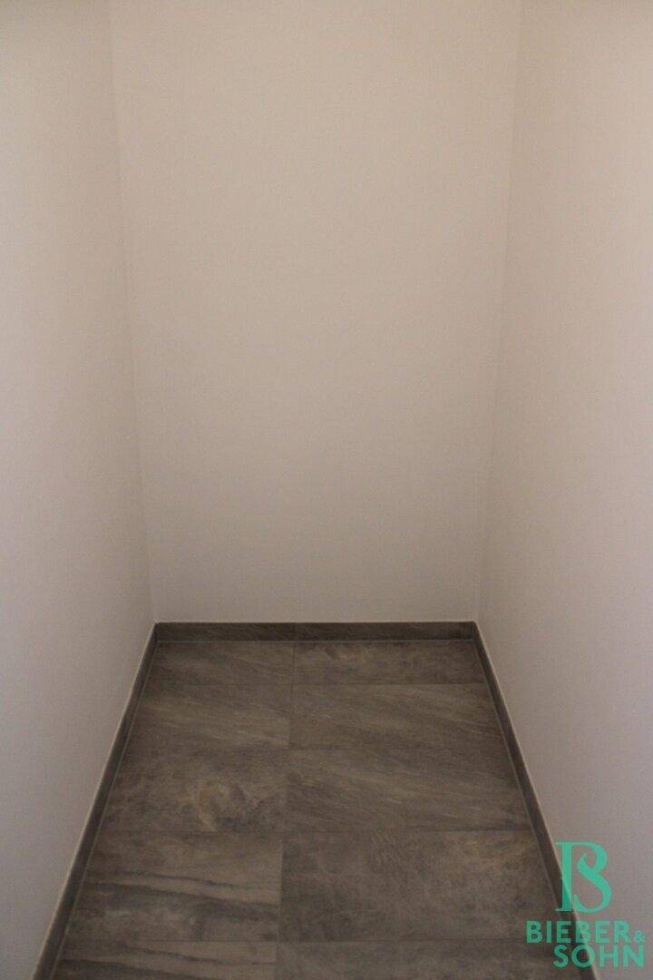 Kleiner Abstellraum mit dunklen Fliesen, ideal für zusätzlichen Stauraum.