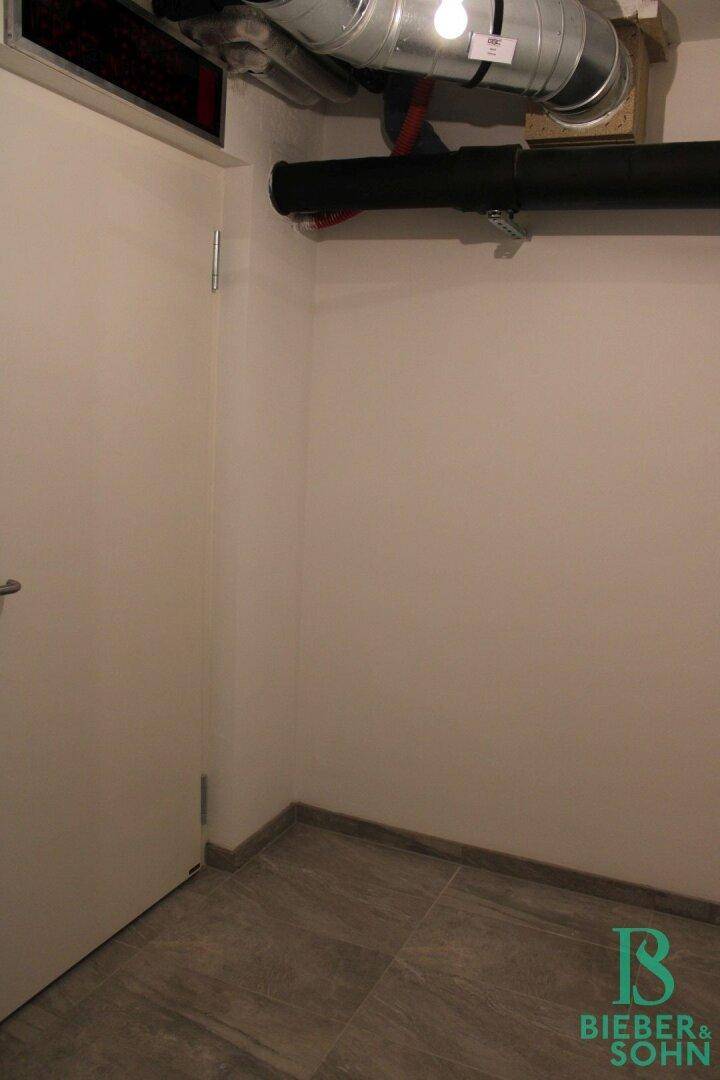 Abstellraum mit Fliesenboden und sichtbaren Rohren unter der Decke.