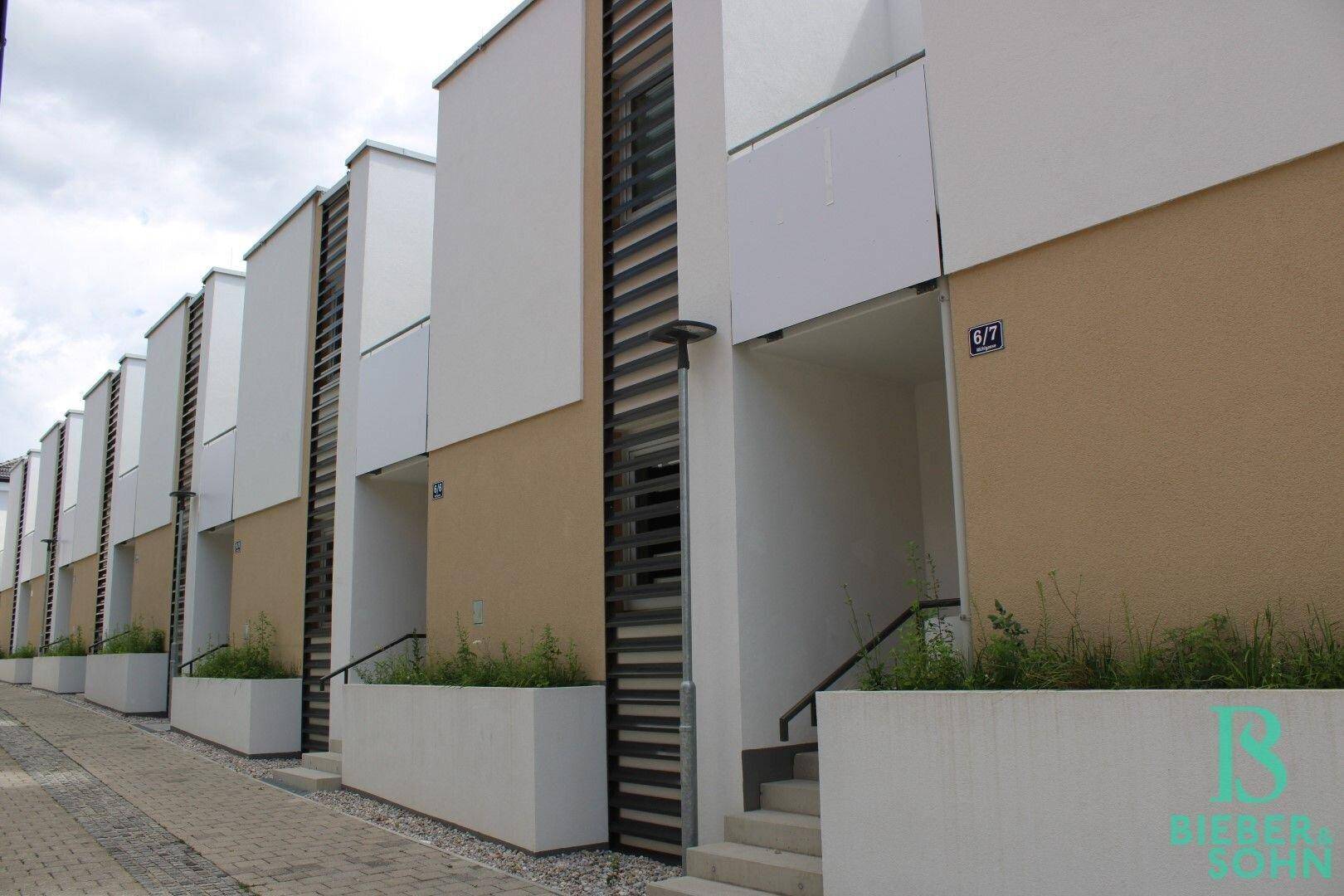 Reihenhäuser mit moderner Architektur und klaren Linien, umgeben von einer gepflegten Anlage.