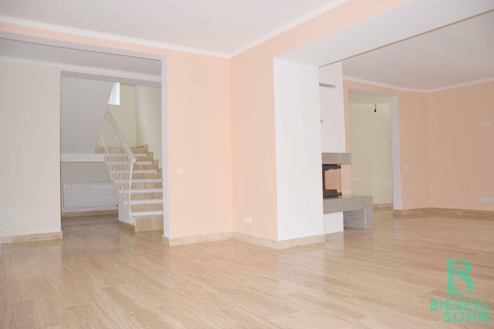 Wohnzimmer mit Kamin, Fliesenboden und offenem Zugang zum Treppenhaus.