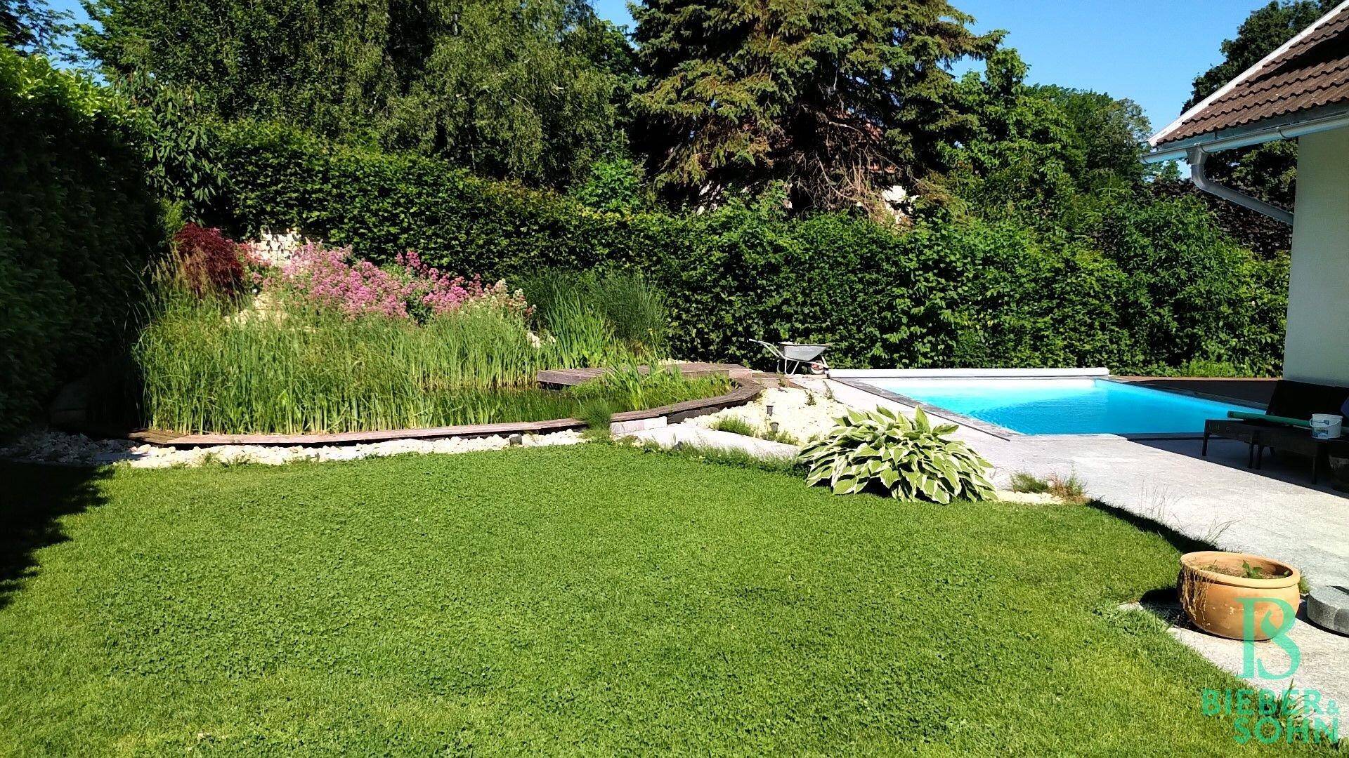 Weitläufiger Garten mit großem Rasen, Schwimmteich und einem erfrischenden Poolbereich.