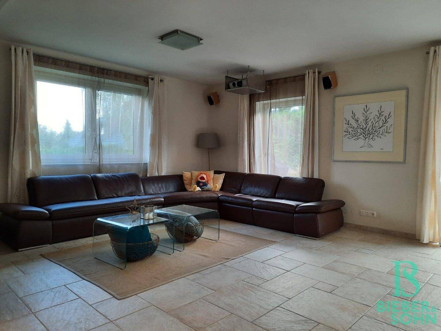 Helles Wohnzimmer mit großem Ecksofa, Fliesenboden und Blick in den Garten.