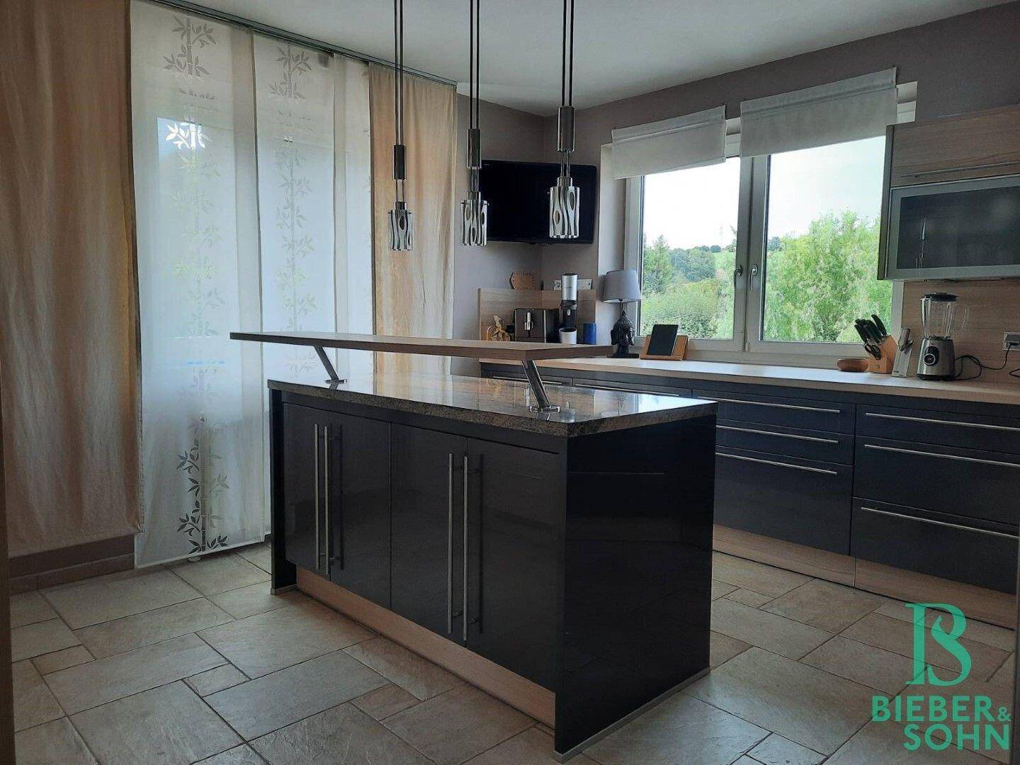 Moderne Küche mit Kücheninsel, Granitarbeitsplatte und großem Fenster mit Ausblick.