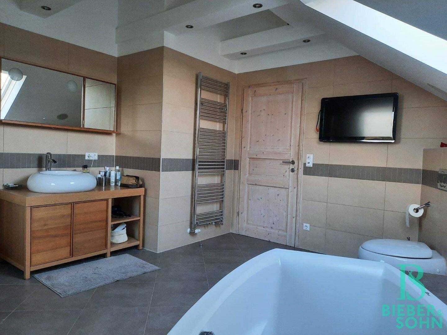 Helles Badezimmer mit Dusche, Badewanne, Waschbecken und beheiztem Handtuchhalter.