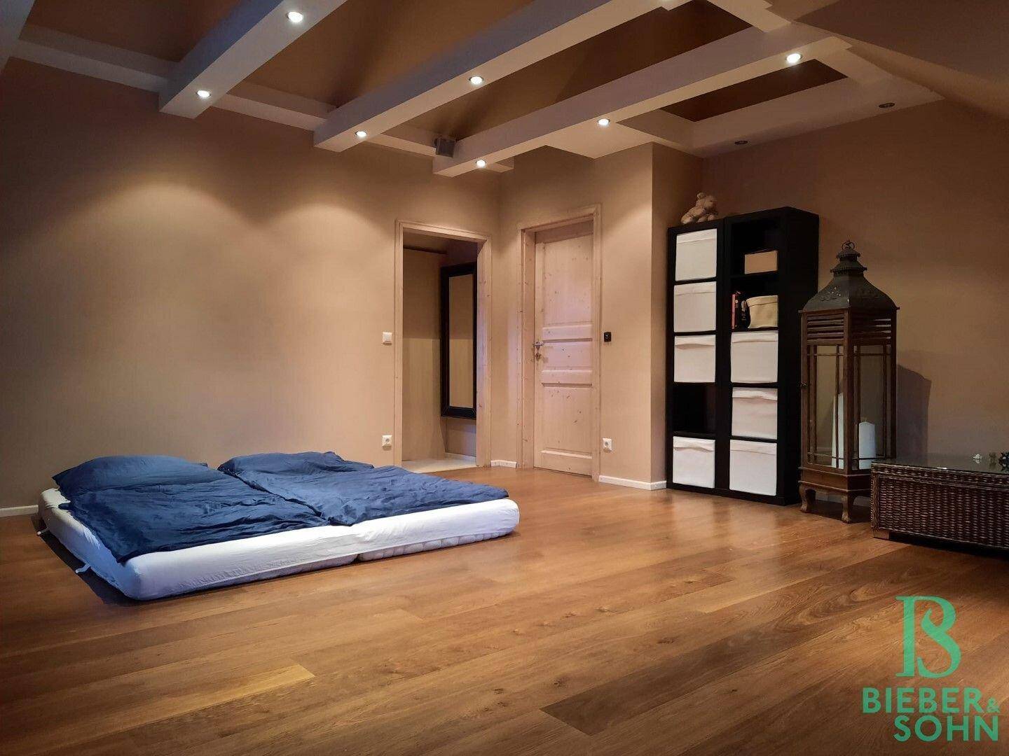 Schlafzimmer im Dachgeschoss mit Holzboden, Dachschrägen und indirekter Beleuchtung.