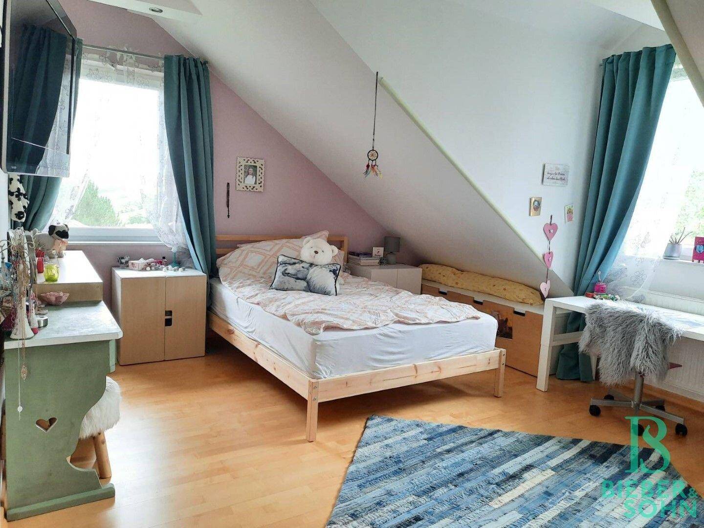 Kinderzimmer im Dachgeschoss mit Holzboden, Dachschrägen und farbenfroher Dekoration.