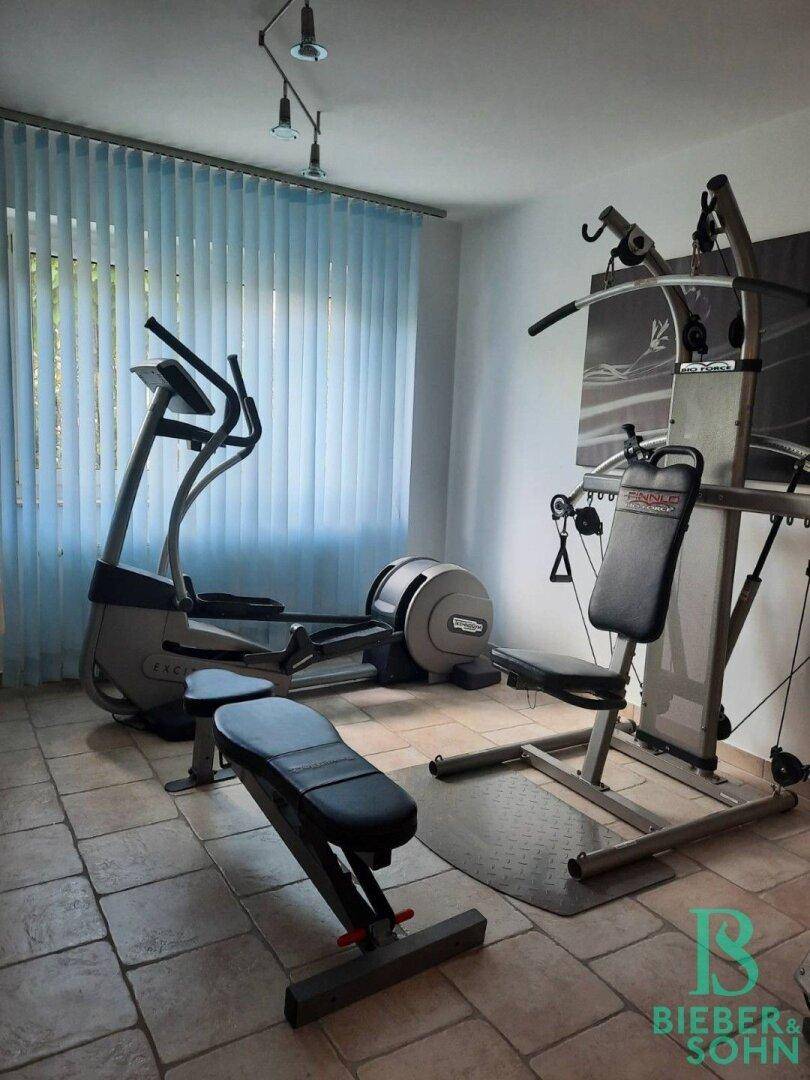 Heller Fitnessraum mit Trainingsgeräten, Fliesenboden und Fenster für natürliches Licht.