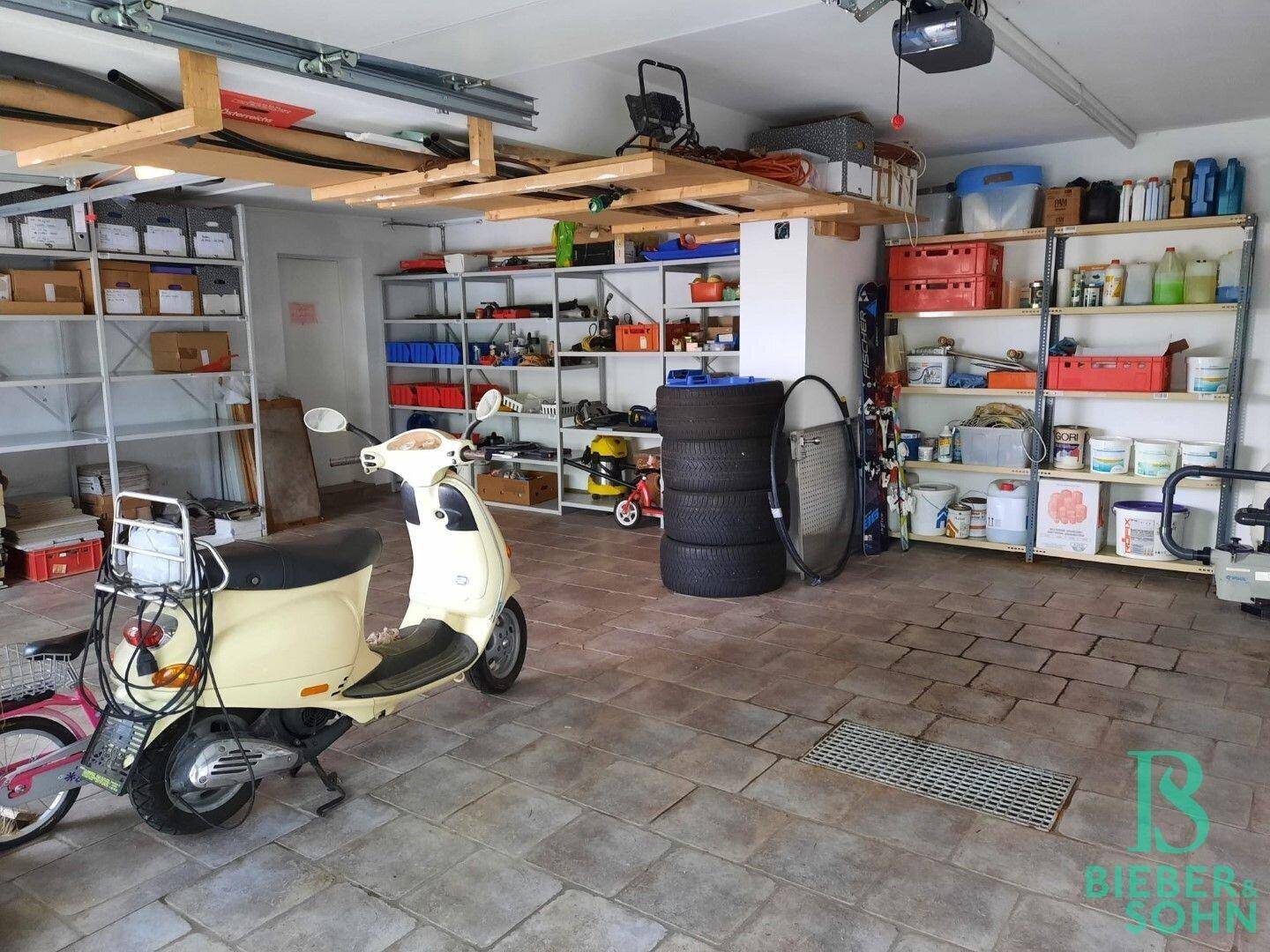 Geräumige Garage mit viel Stauraum, Regalen und Platz für Fahrzeuge und Werkzeuge.